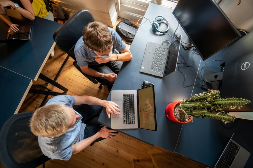 två män sitter bredvid varandra och jobbar på laptops