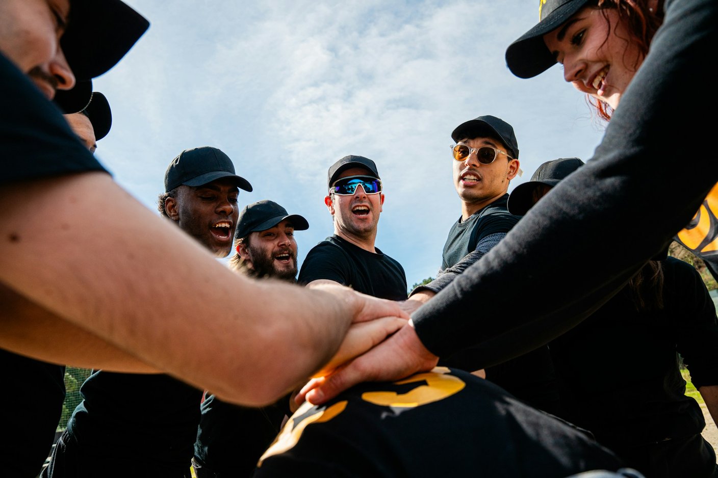 team som står i cirkel och håller händerna ovanpå varandras händer