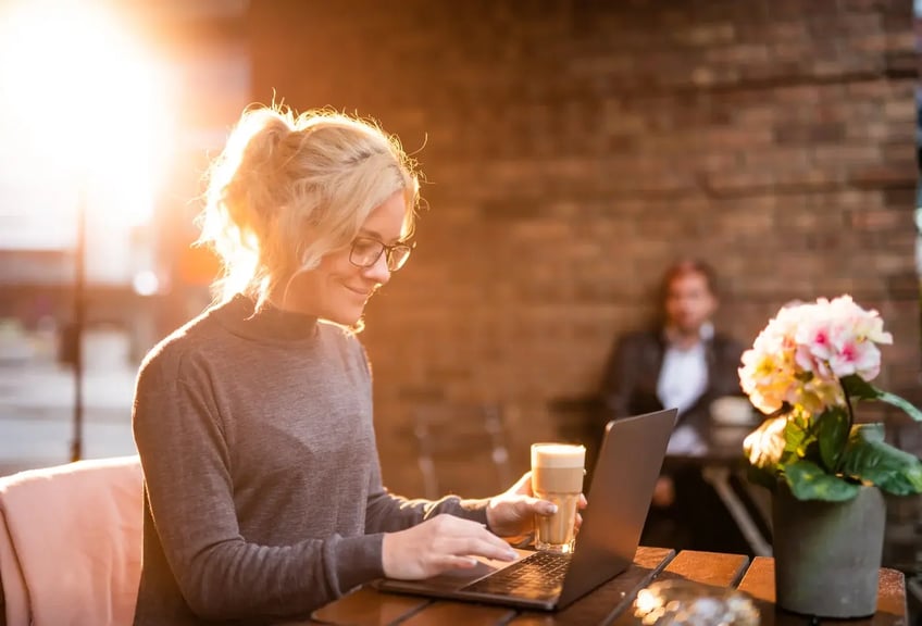 kvinna med kaffekopp vid dator