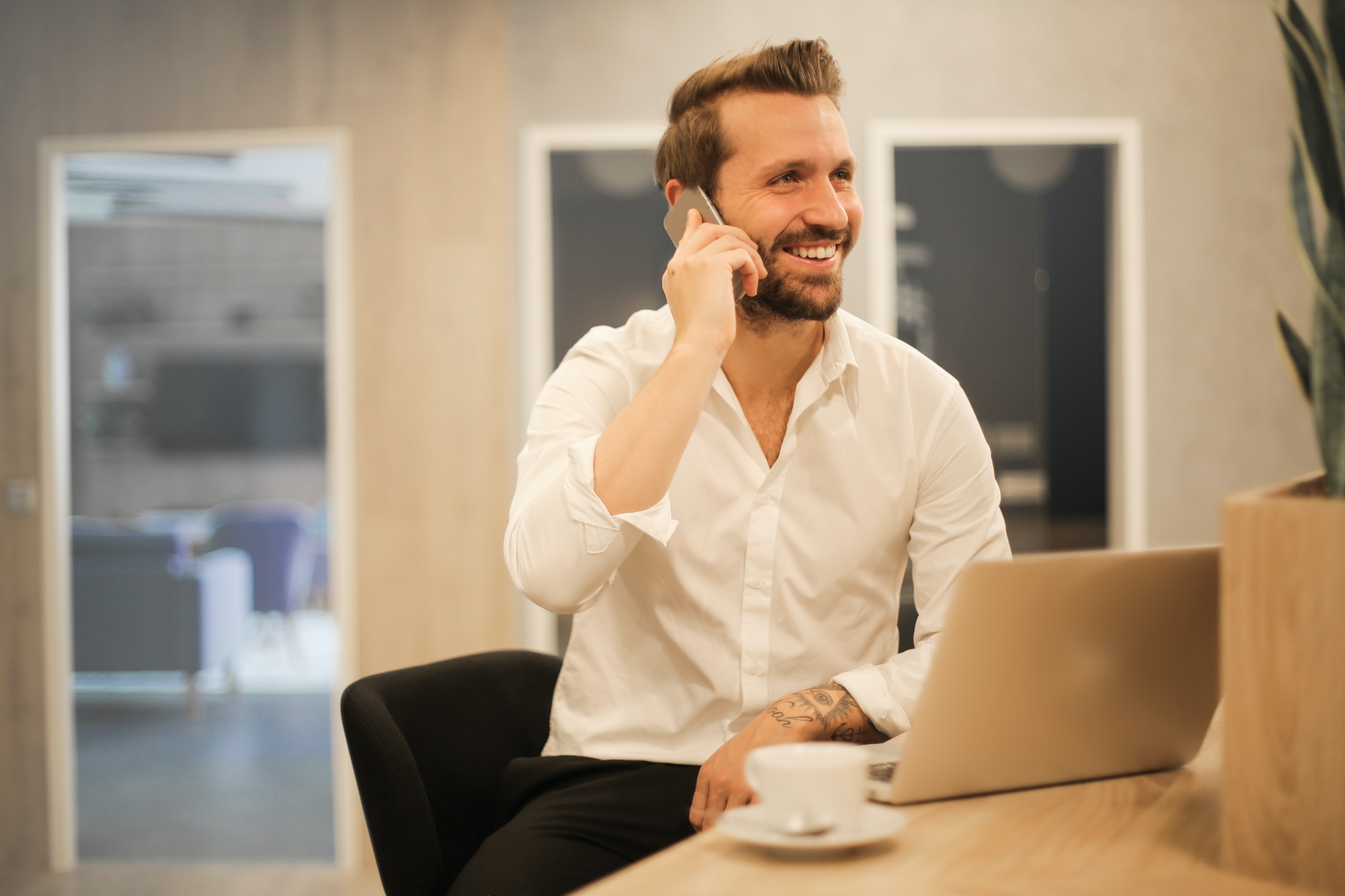 leende man pratar i telefon vid dator