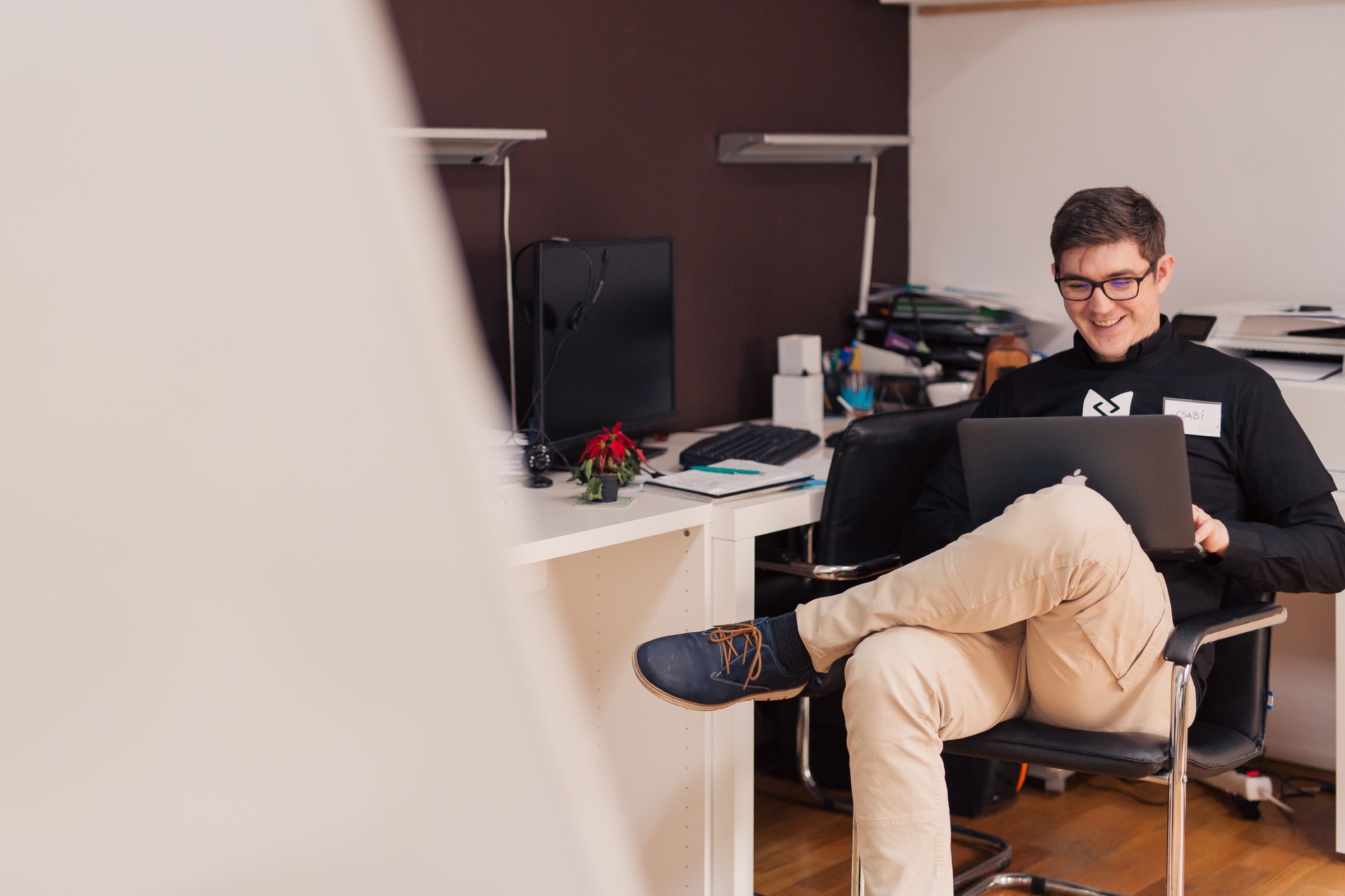 leende man sitter i stol med laptop i knäet
