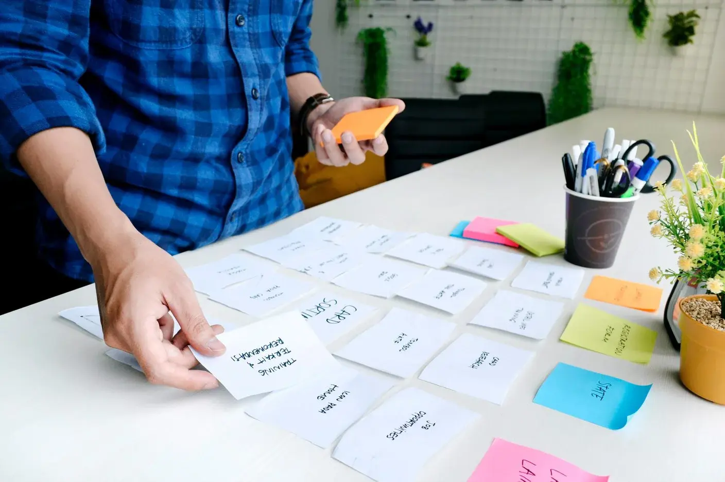 man som står vid skrivbord och flyttar post it lappar